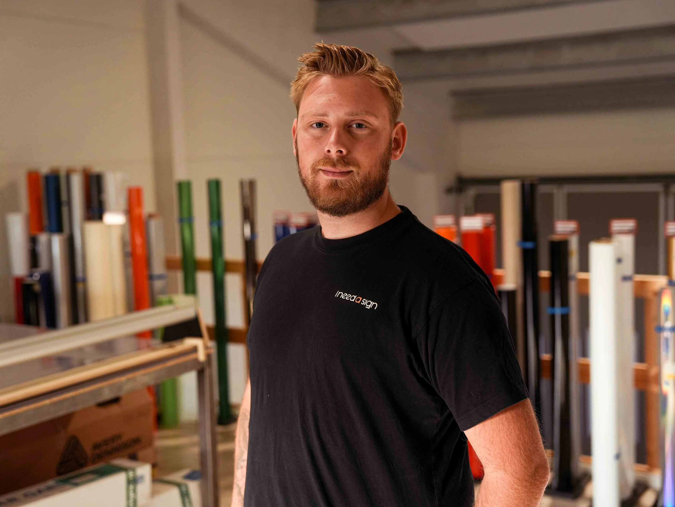 Patrick fra I need a sign står foran reolerne med folieruller i værkstedet
