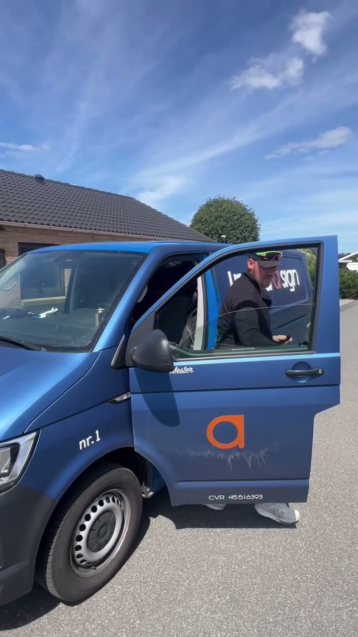 Patrick fra I need a sign ved den blå firmabil med døren åben